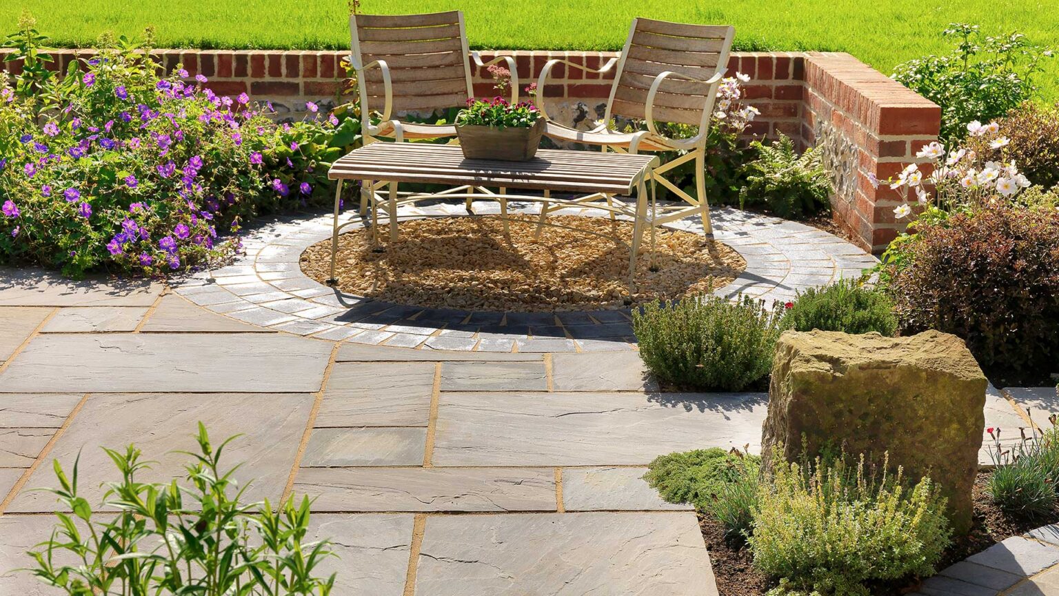 A red brick knee wall enclosing three sides of this seating areas, with black limestone paving blocks and grey sandstone slabs.