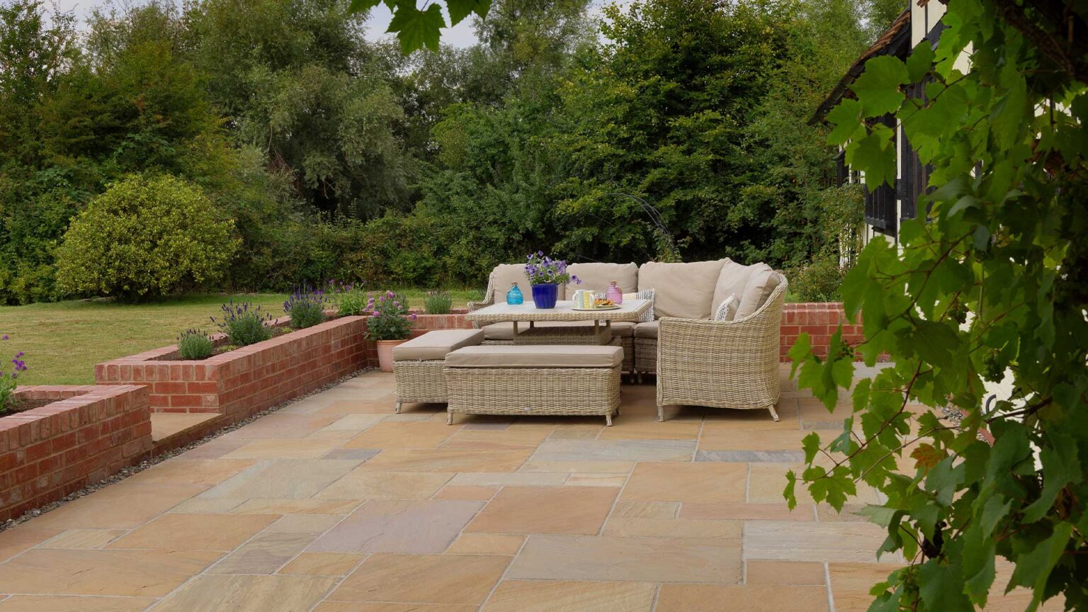 This buff sandstone patio is enclosed with a raised bed parapet wall of red bricks, with a soldier course on the top row.