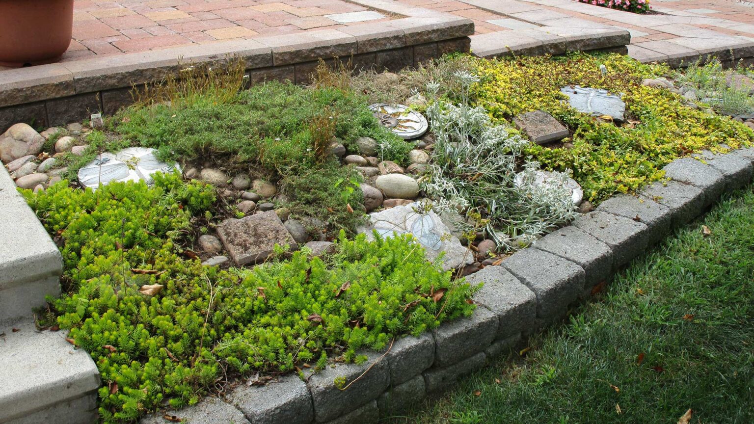 Stone-fffect concrete ankle wall retaining a low alpine rockery