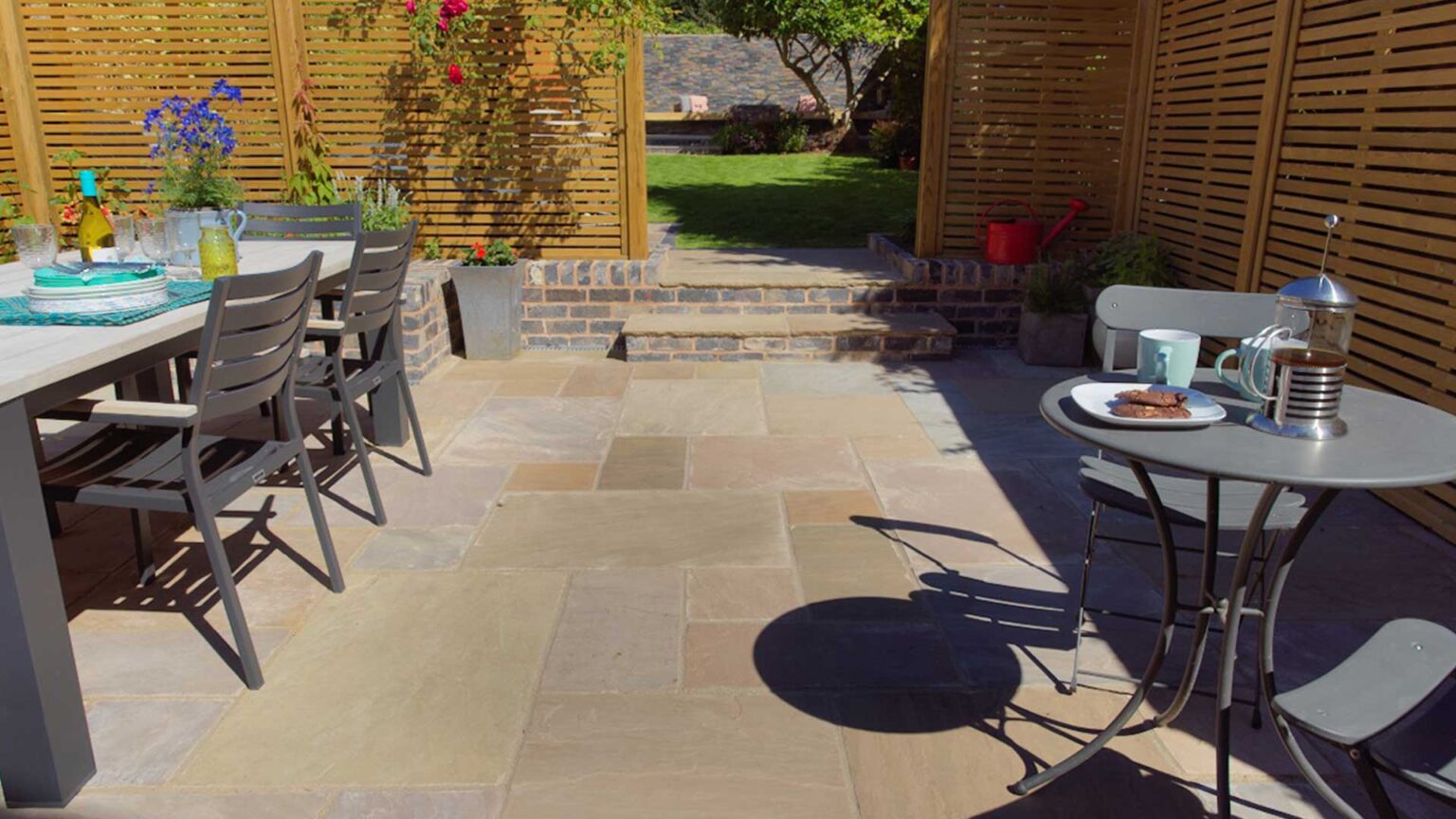 Black brick face on the lifts of these terrace steps with Raj Blend sandstone treads separating the rooms of the garden.