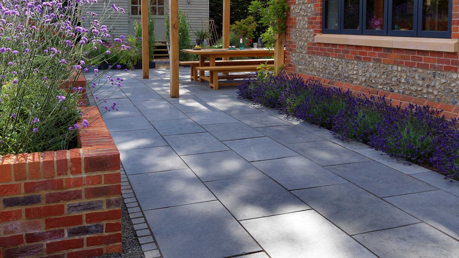 Red brick raised flower beds to match the brick and flint walls of the house.