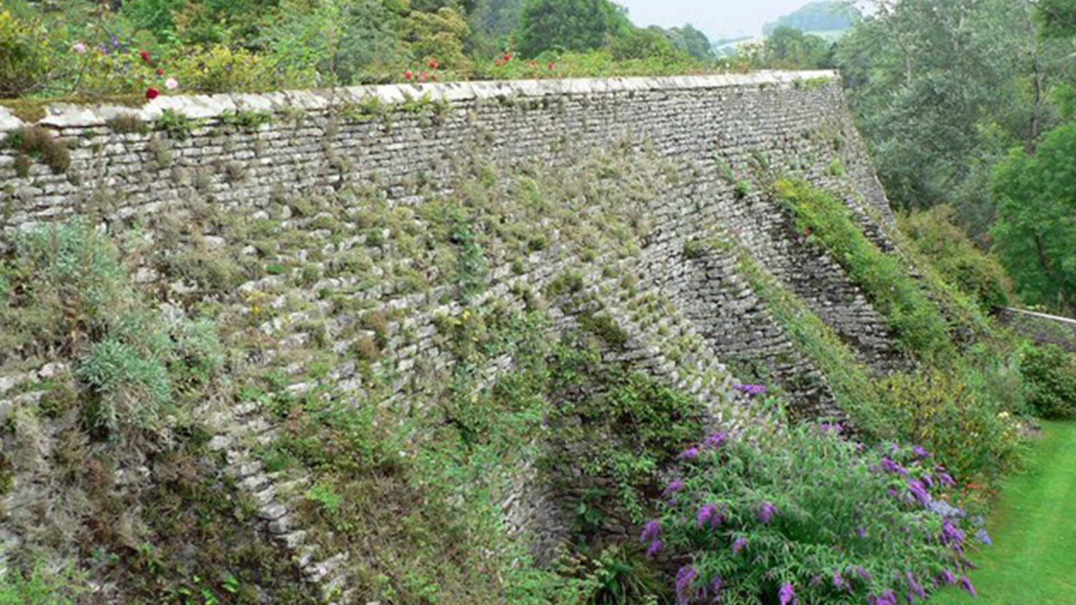 A limestone buttressed and inclined retaining wall on between garden terraces.