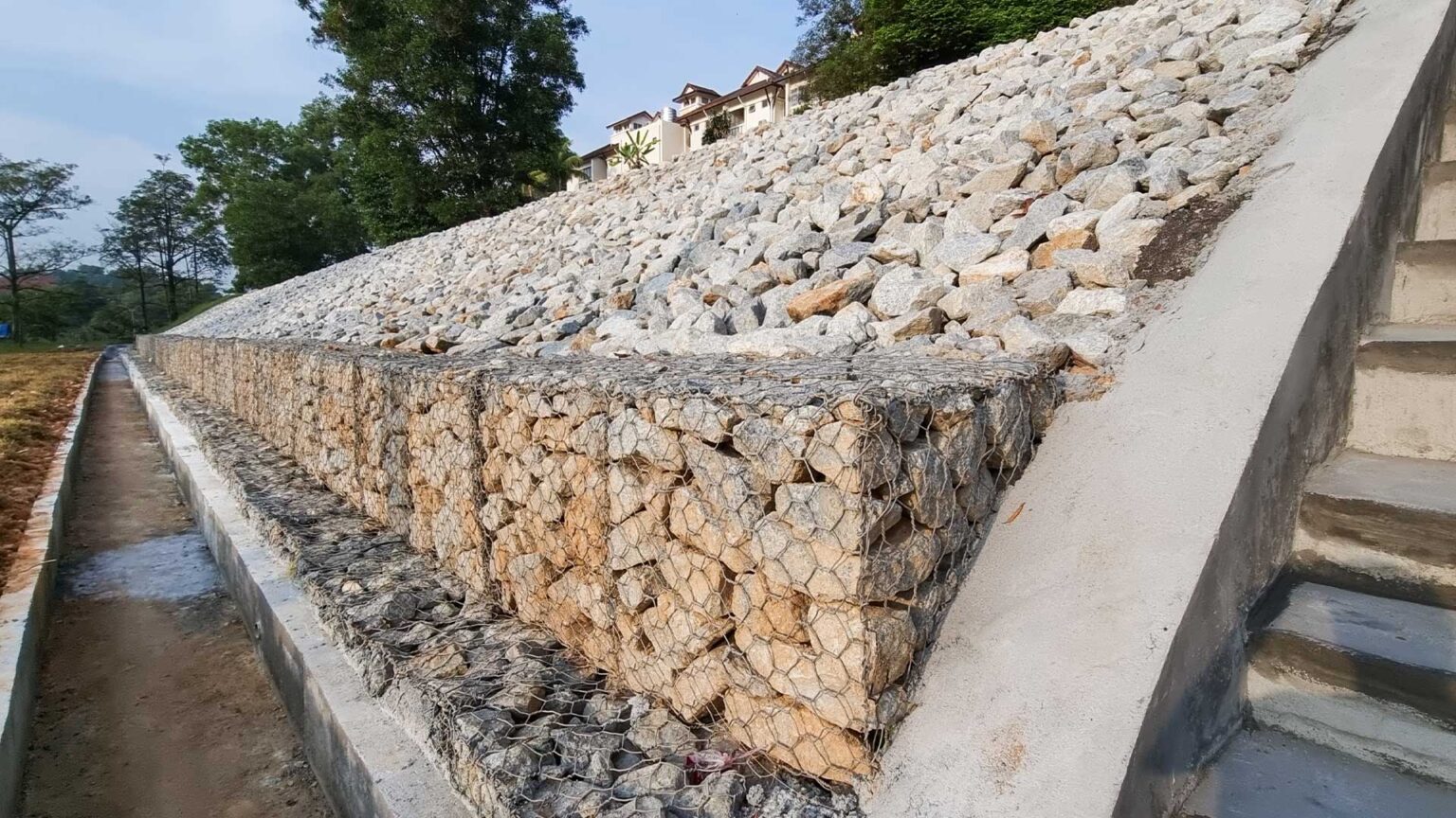 Limestone boulders in an inclined retaining wall with gabion baskets footings.