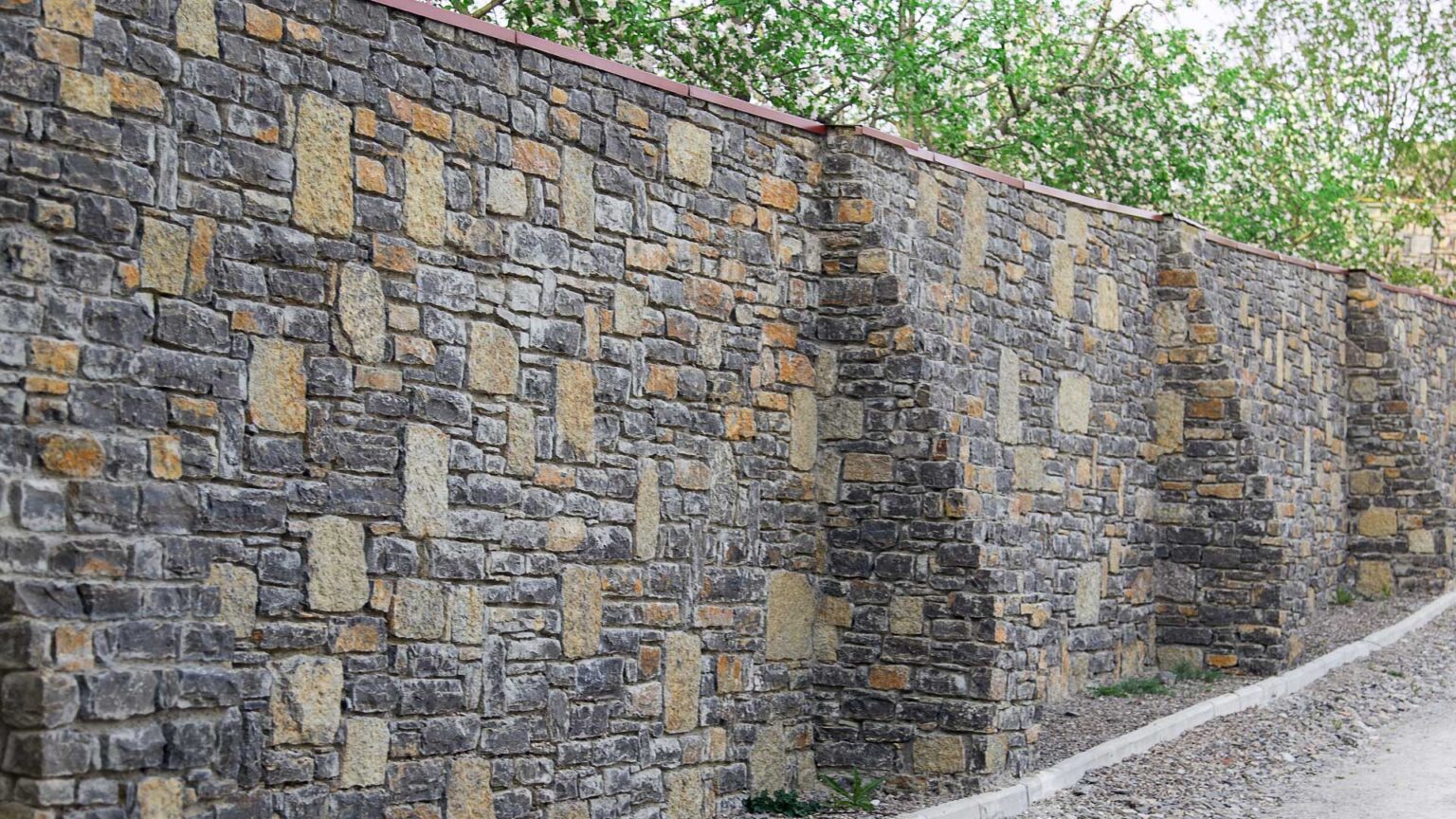 A limestone and basalt bound stone retaining wall with buttresses.