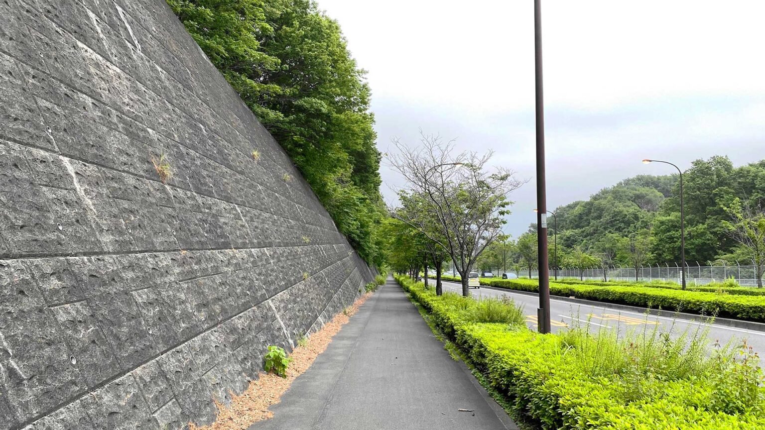 An inclined concrete block retaining wall with a decorative granite-effect finish. This high retaining wall is likely to be using anchors for additional strength.