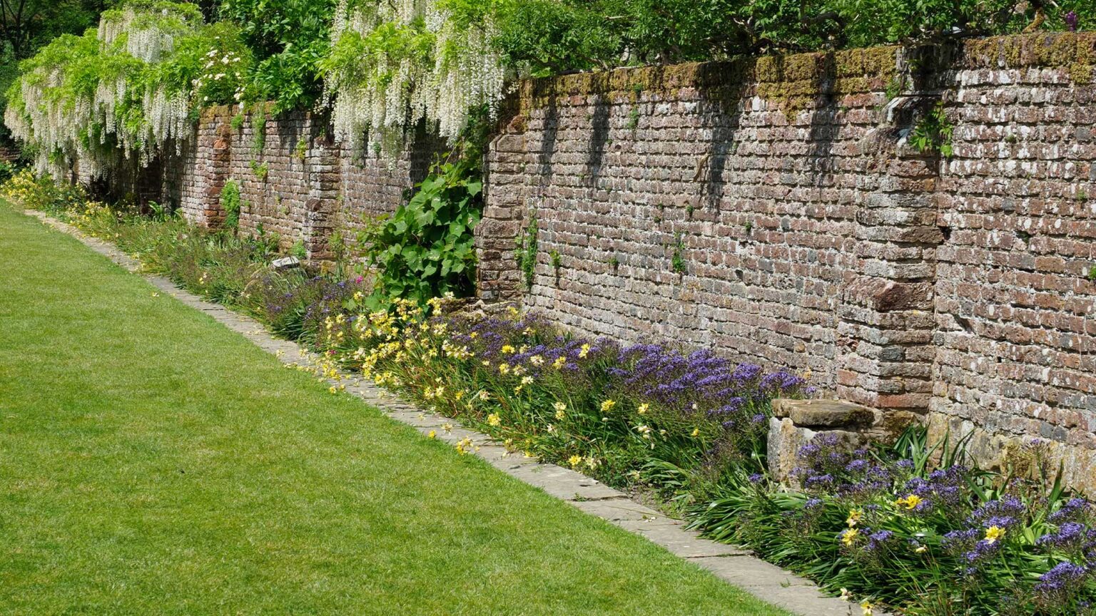 A rustic garden brick wall with pseudo piers/buttresses with plinth steps.