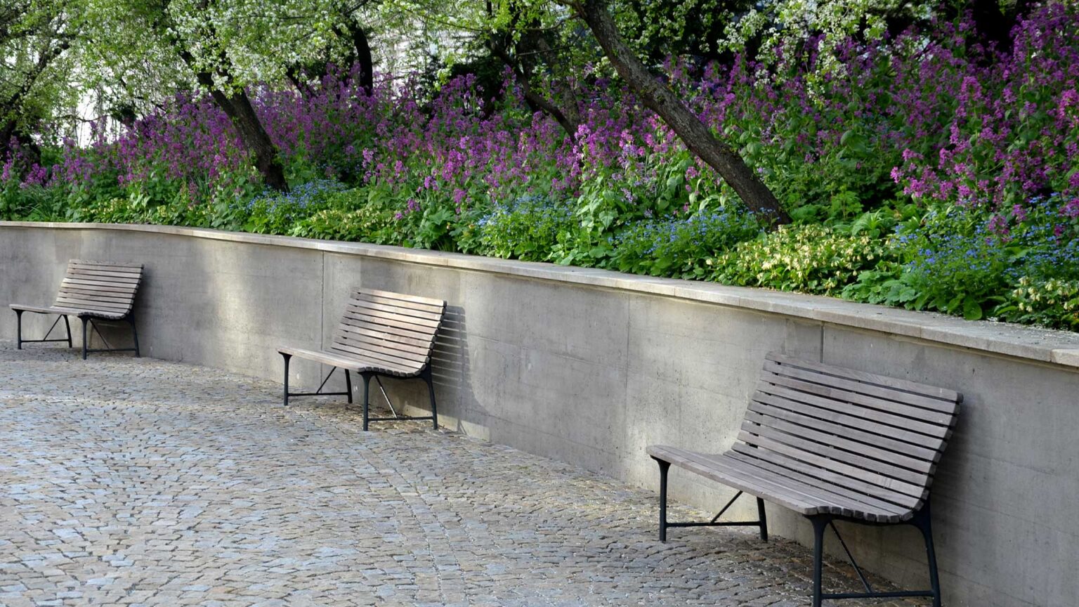 This public park features a robust, poured concrete retaining wall, seamlessly blending with landscaped greenery for a modern, utilitarian and durable design.