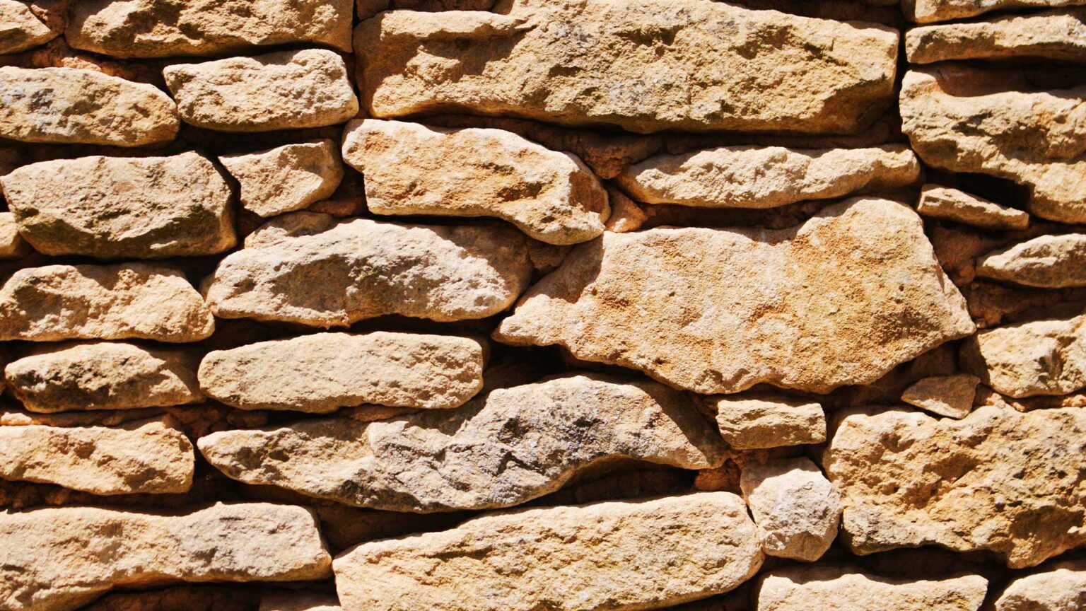 A traditional oolitic limestone wall constructed using dry stone building techniques.