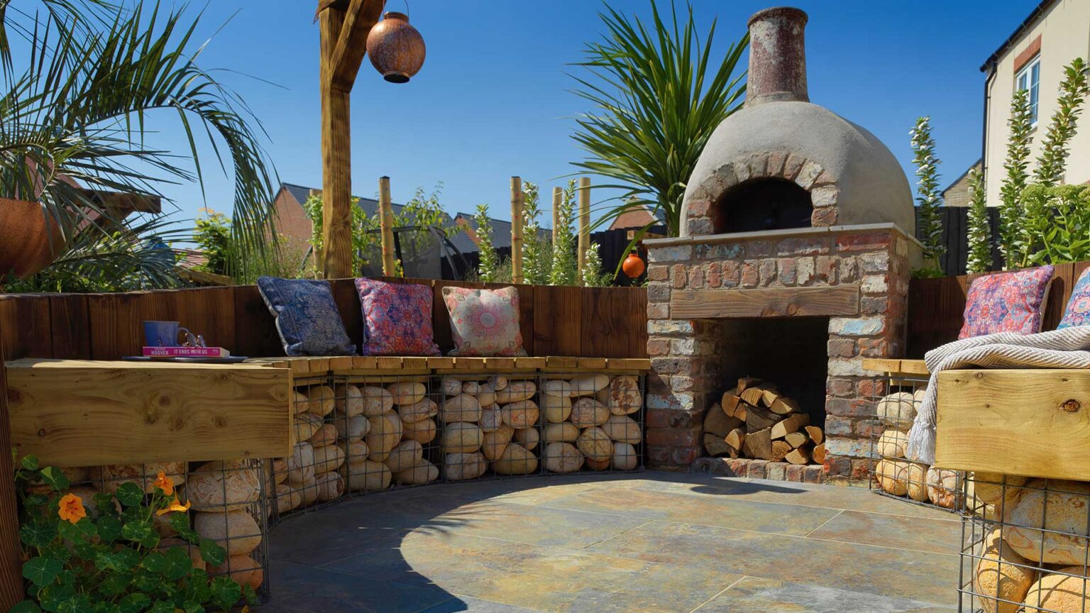 Gabion baskets filled with large river cobbles forming a dwarf seating wall around this exterior fireplace.