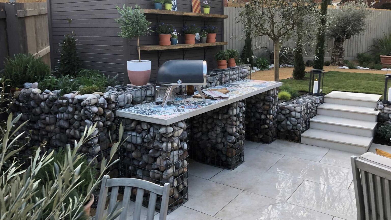 An outdoot kitchen using river cobble filled gabion cages for the walls and worktop plinths.