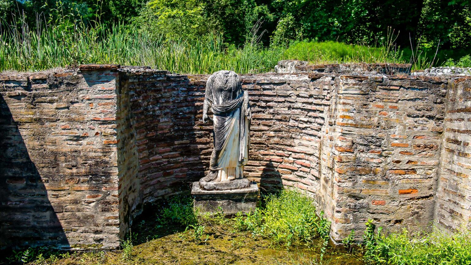 A Roman dwarf wall with recessed nook containing a headless senatorial statue. Notice ratio of mortar to brick.