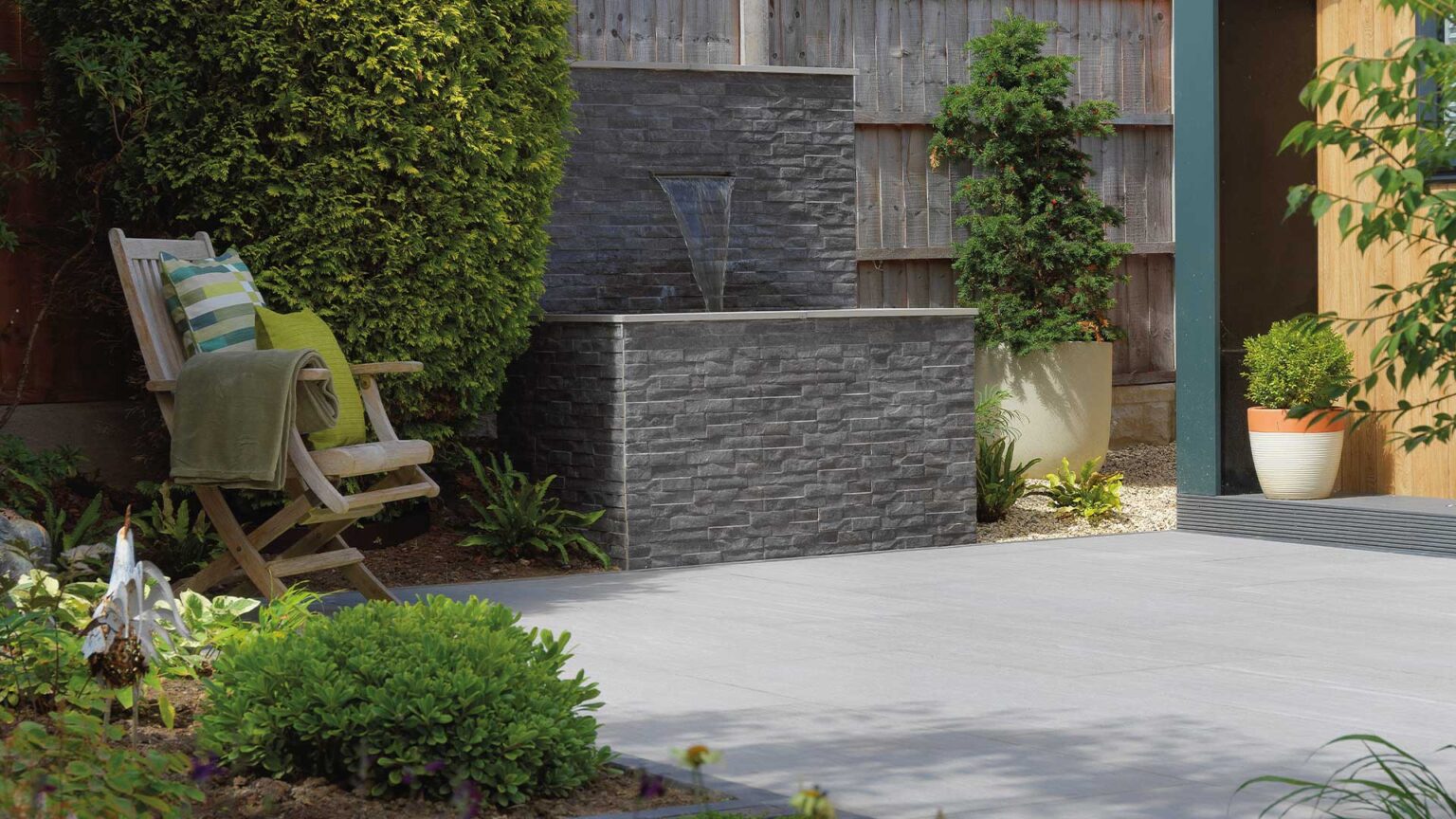 A raised pond with scupper fountain running into it. The wall and pond are clad with porcelain rockstack cladding.