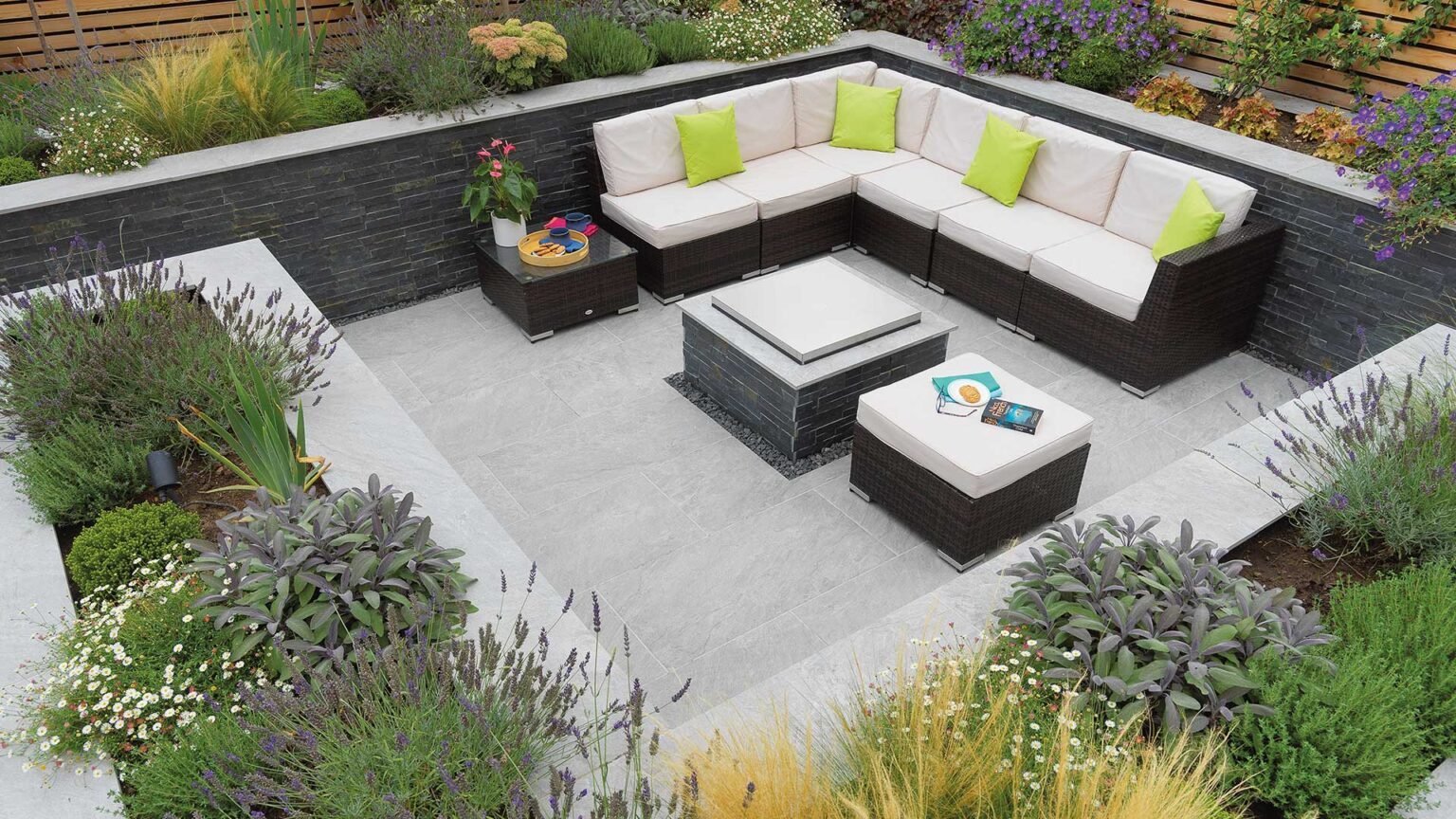 A sheltered contemporary sunken garden with sofa & fire pit. Materials: porcelain Rock Stack cladding and Dolomite Porcelain paving & coping.