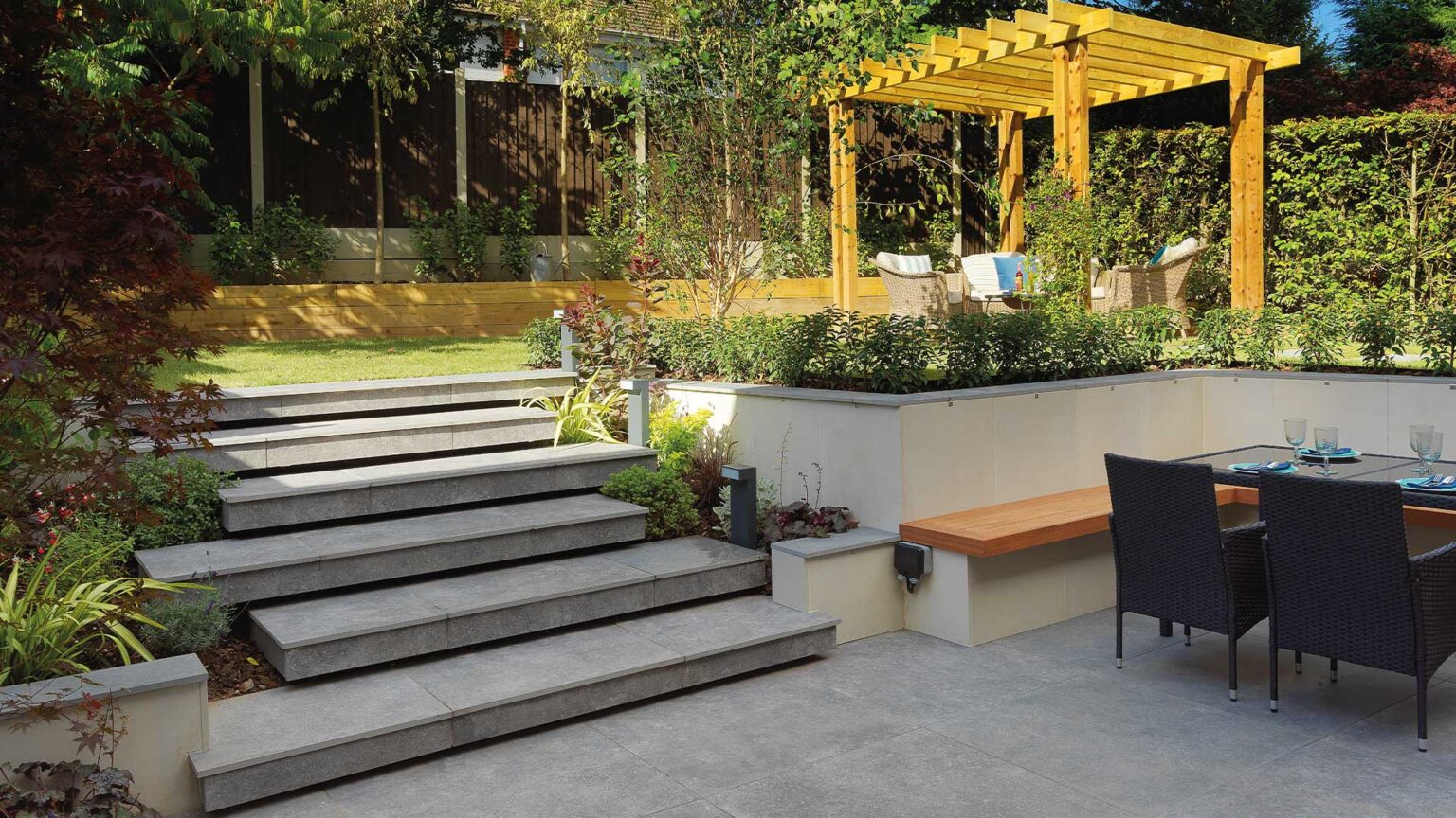 Staggered porcelain steps with under step lighting between the dining and seating terraces of this garden.