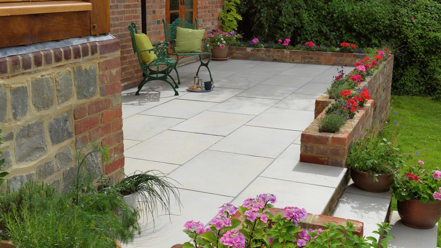 A paved terraced with a raised bed parapet wall in matching red brick to the property (as are the step risers).