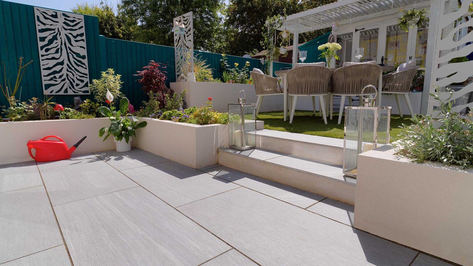 The retaining knee walls of the raised beds that surround this patio and outdoor dining area, provide a clean and elegant border to these spaces.