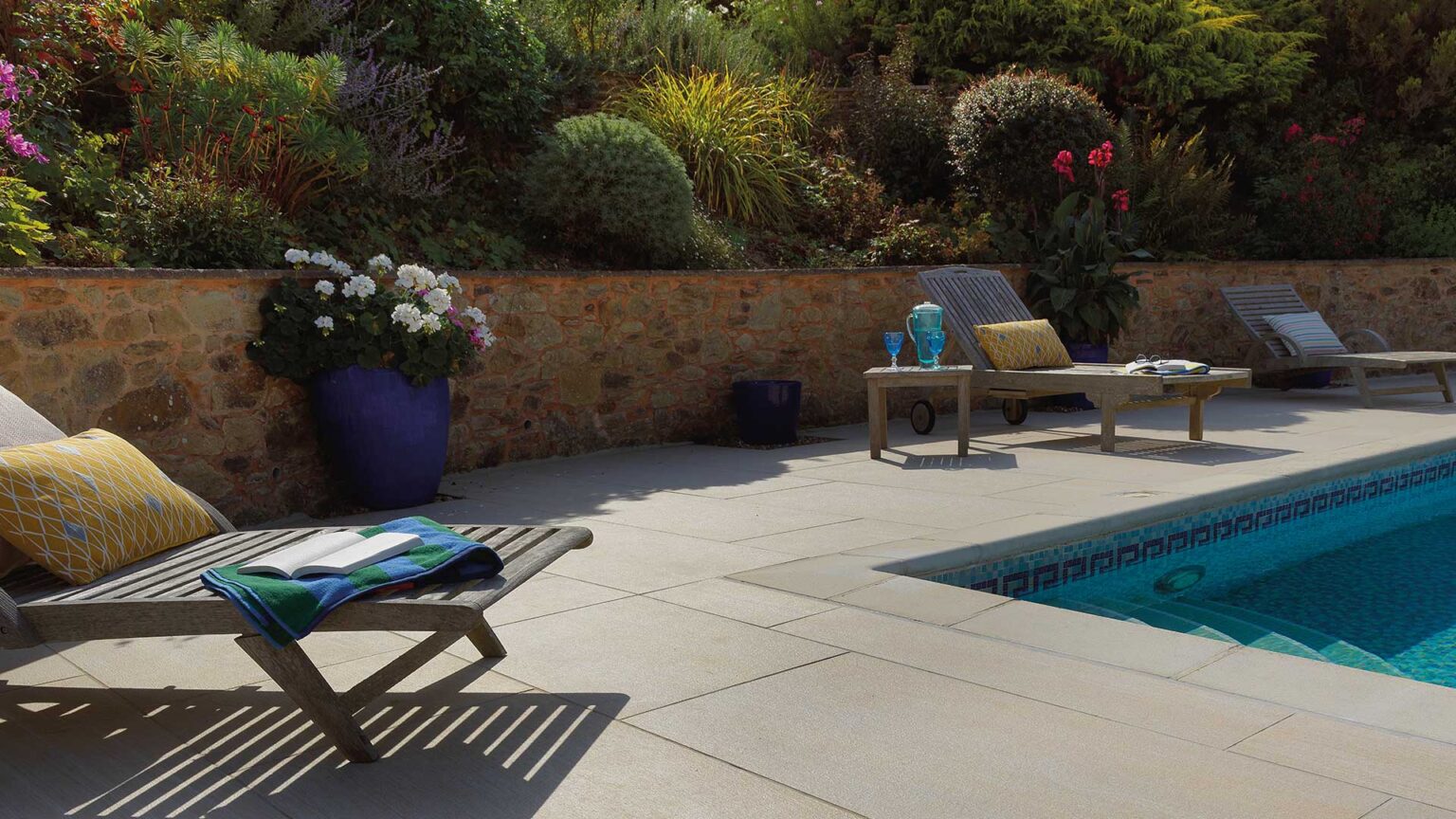 A bonded sandstone retaining wall provides a Mediterranean look and feel to tie in with the Greek style geometric mosaic design of the pool.