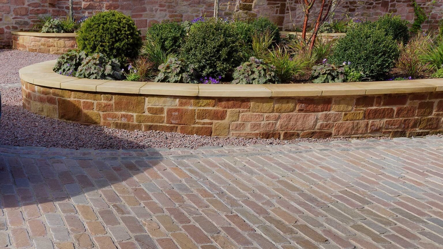 An elegant bonded yorkstone raised bed with buff coping stones