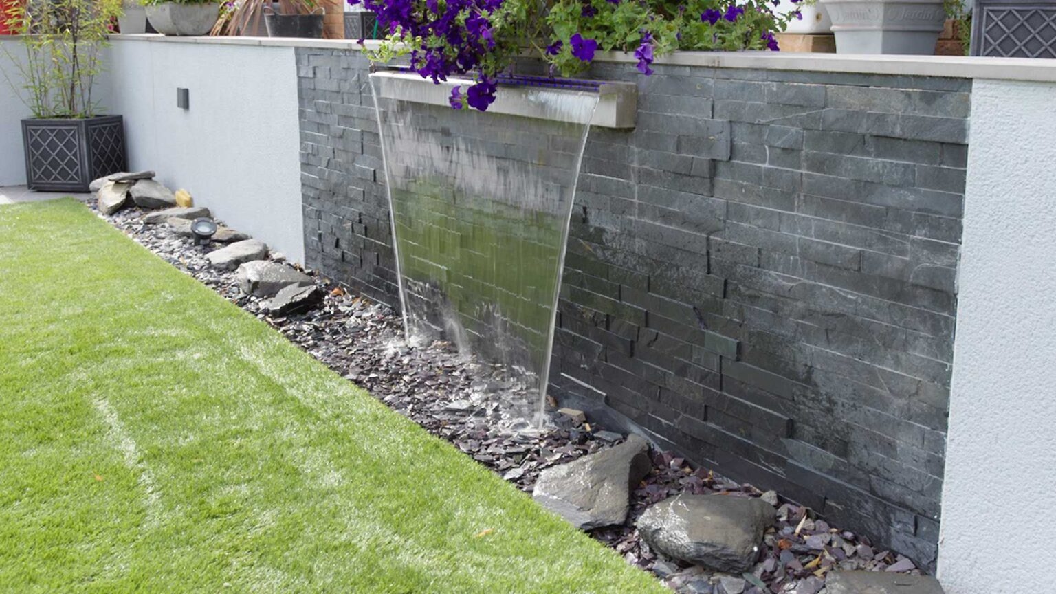 Blue black slate cladding used here on this lovely scupper water feature built into the retaining wall.