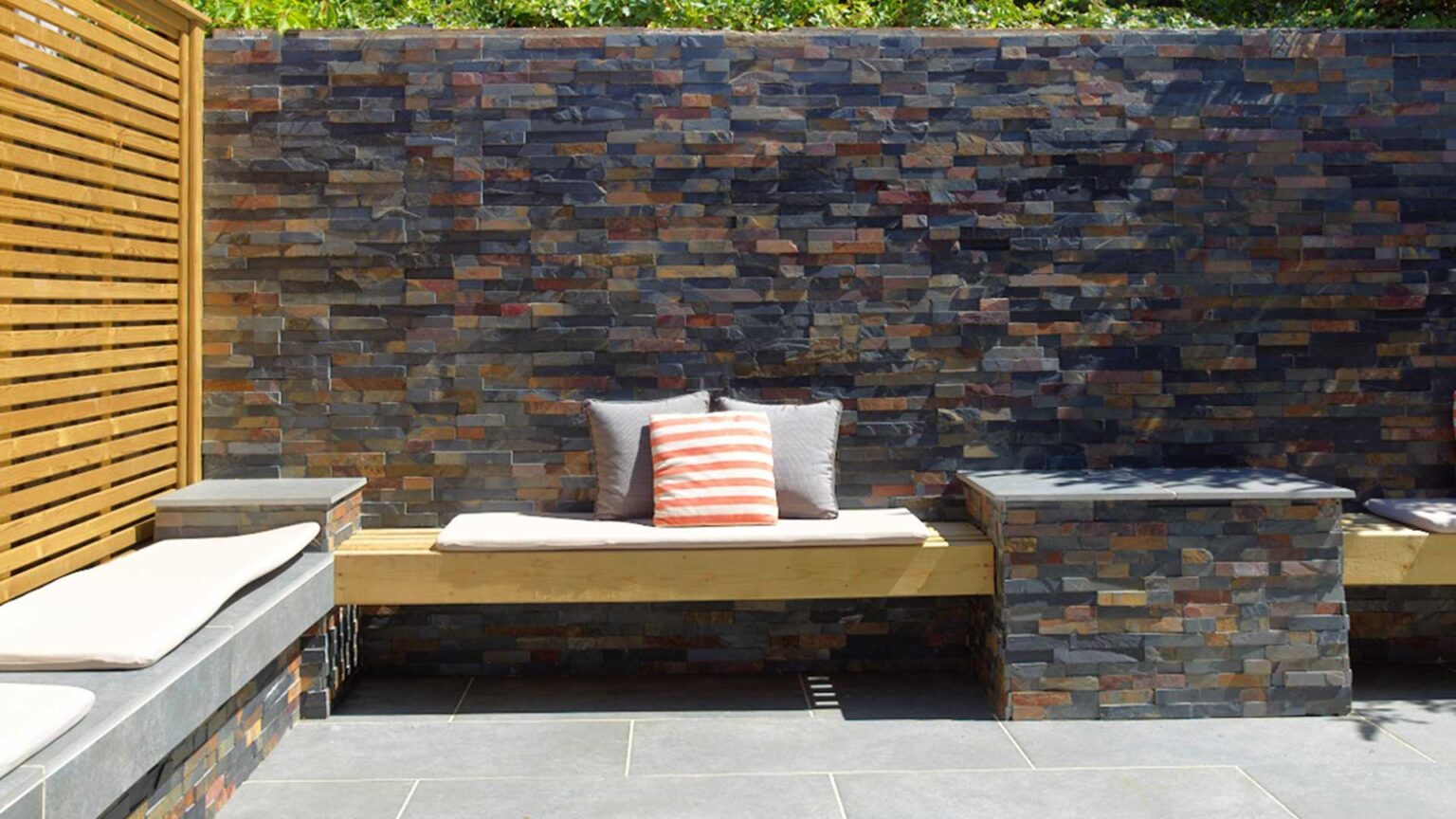 This garden sun-trap is clad with split-face slips of rusty slate to create a stunning natural stone surface on the wall.