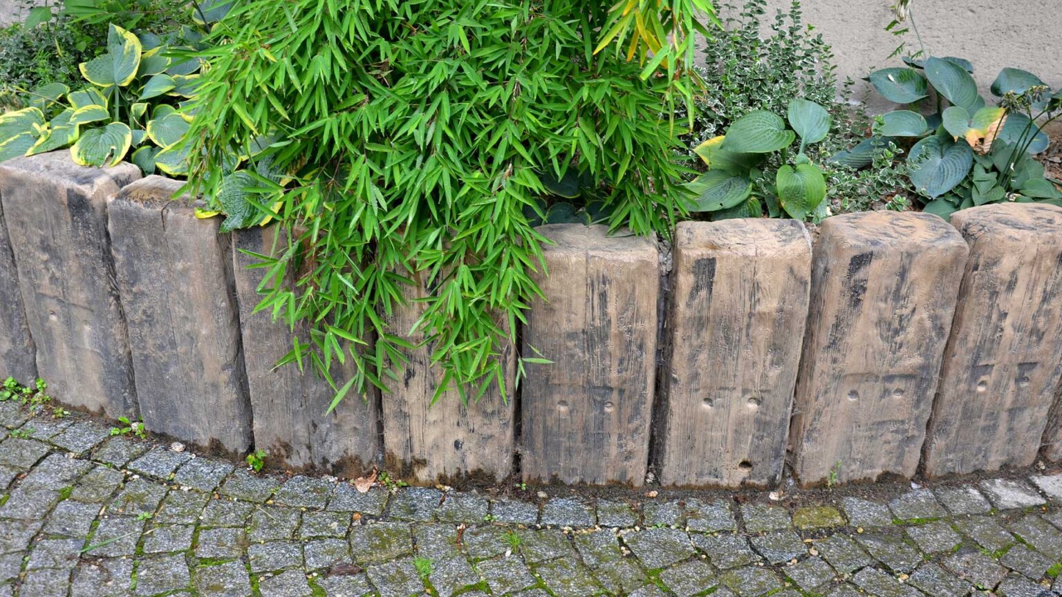 Timber sleepers set into the ground vertically to be used as posts to retain this raised bed.