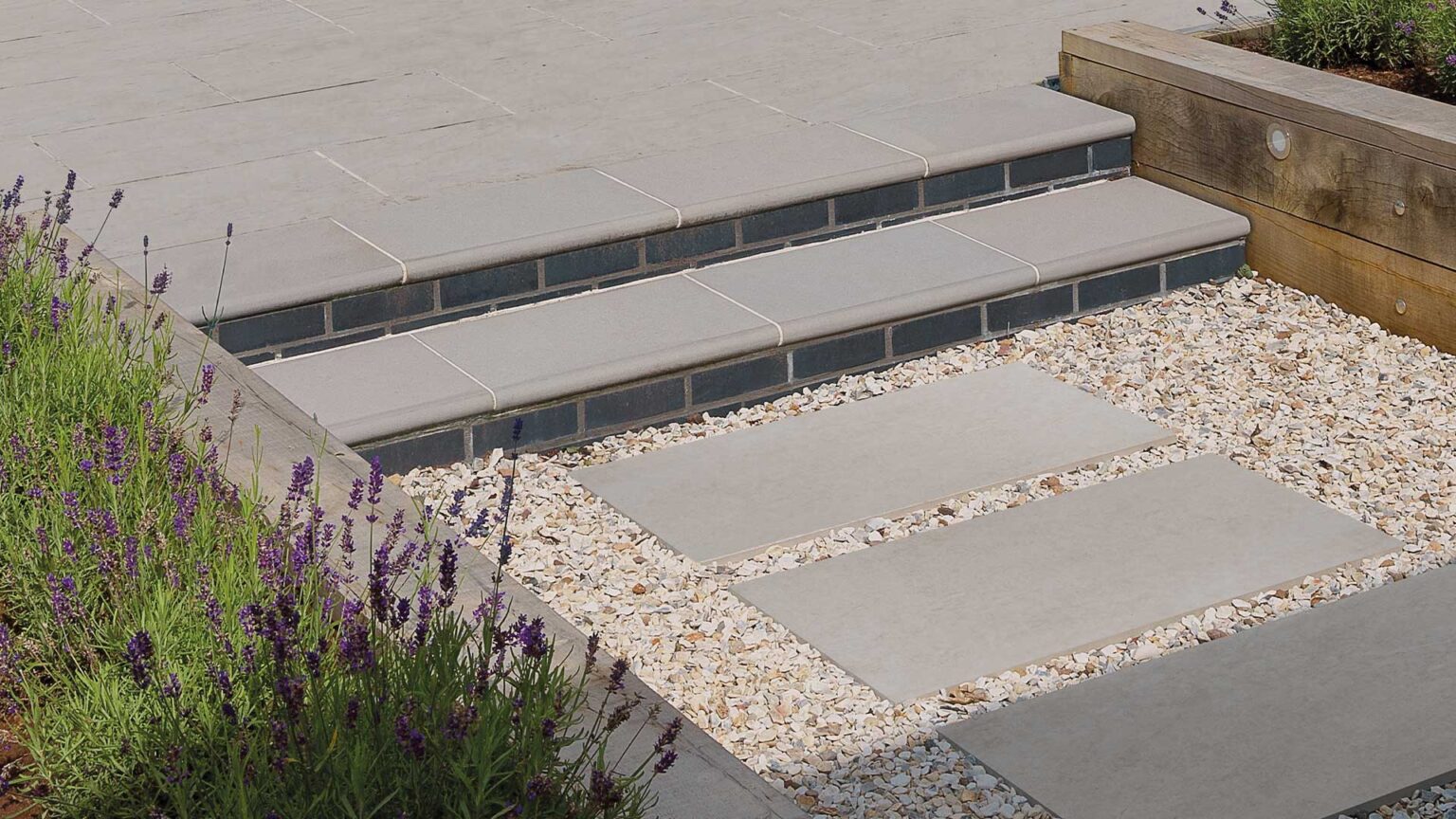 Bullnose Summit Sandstone Steps with black engineering brick riser faces, flankded by timber sleeper retaining walls.