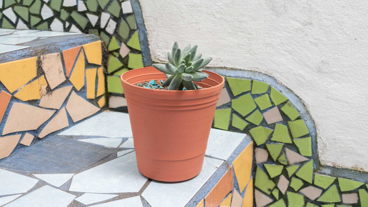 Broken tiles laid to create three separate colourful mosais on the steps, risers and stringing of these steps.