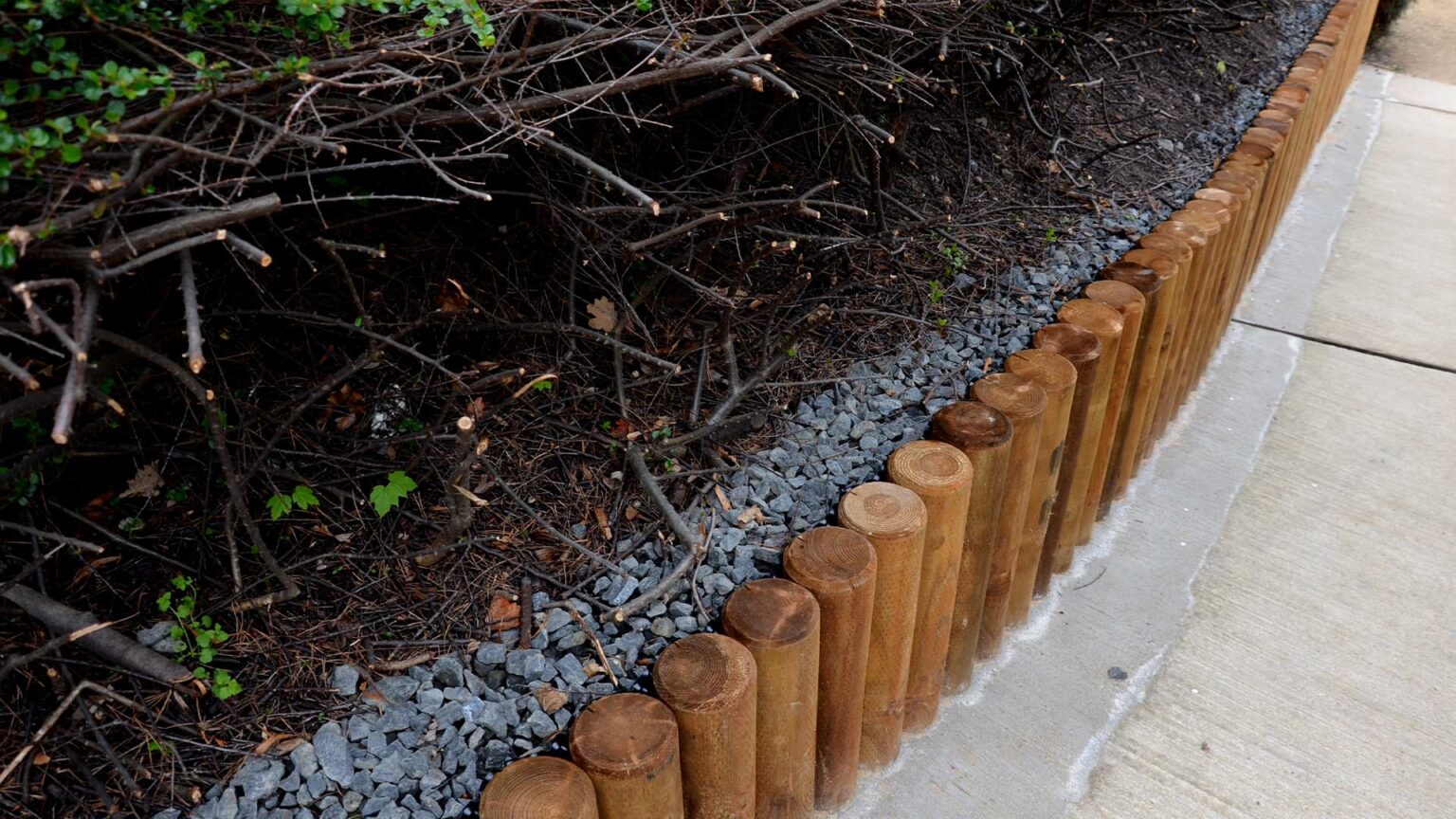 Wooden posts forming thie knee wall. Notice how the backfill area has a stand-off drainage space of aggregate to protect the wooden posts.