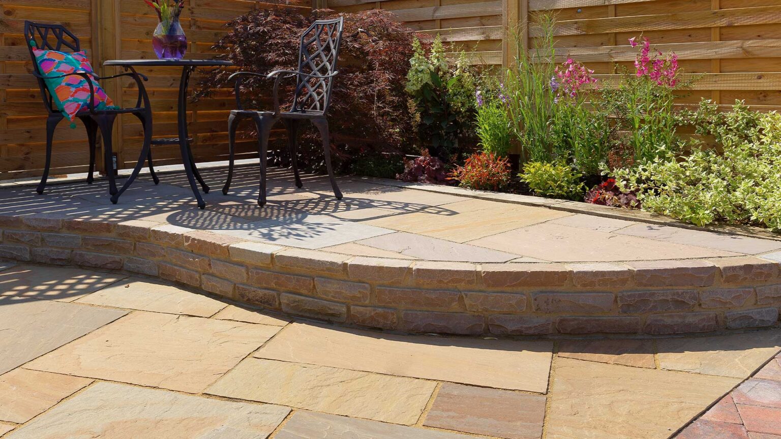 A sandstone block ankle wall retaining a small terrace platform on this patio.