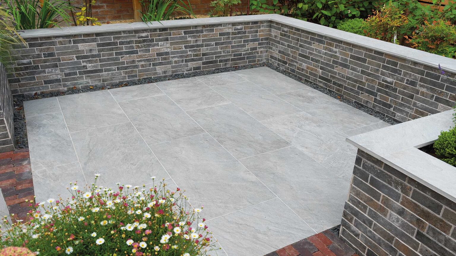 A brick-effect porcelain cladding used here in this sucken garden in combination with a porcelain patio and coping stones.